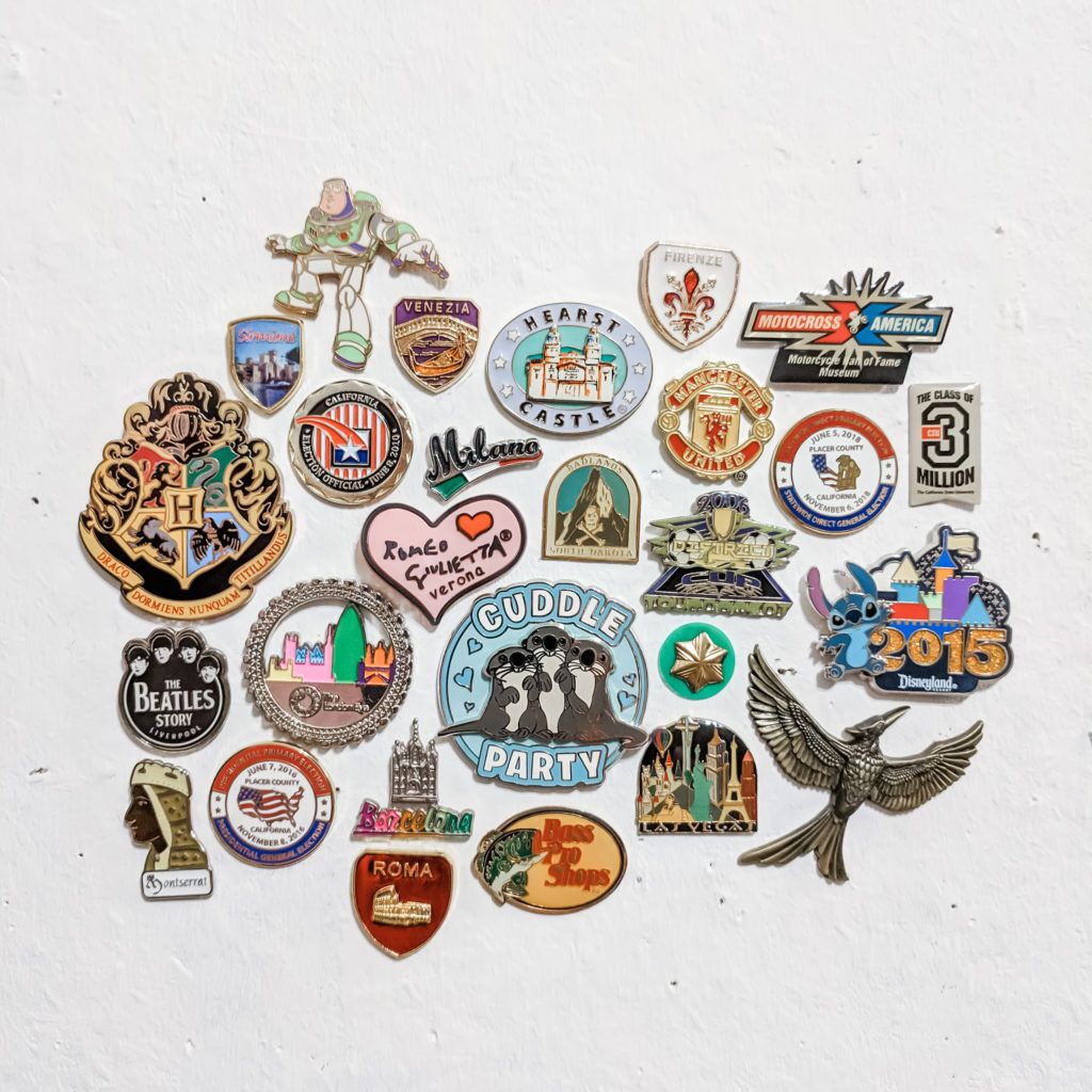 Lots of metal enamel pins from places all over the world on a white background