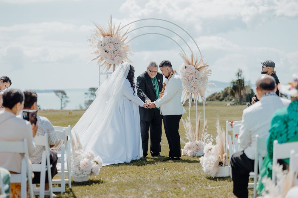 Wedding ceremony under a circular arch decorated with dried pampas grass arrangements.