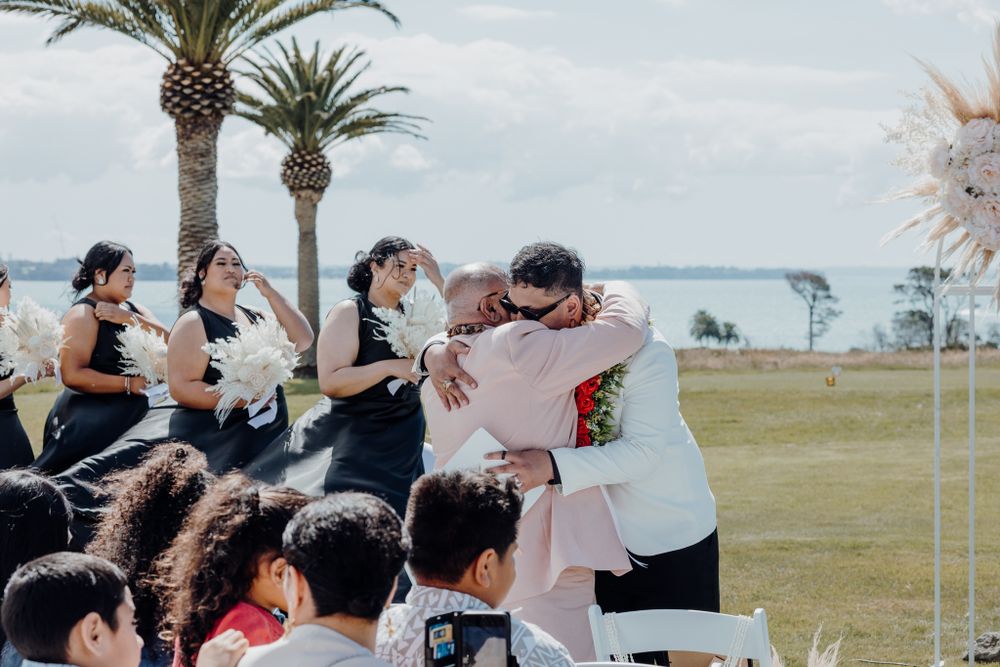 Emotional moment during outdoor wedding ceremony with bridesmaids in black dresses watching.