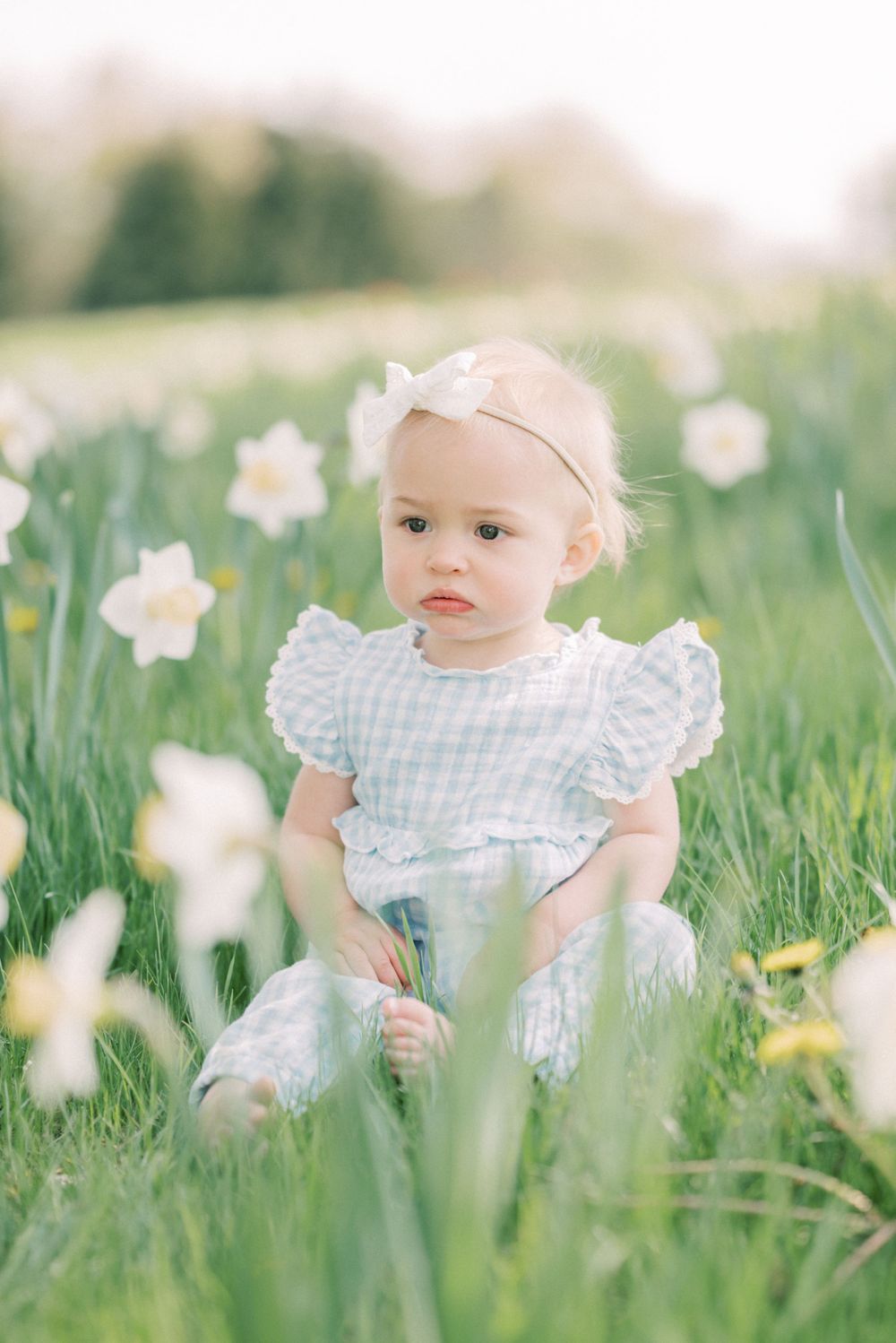 Charming spring portrait amid blooming daffodils in soft pastel tones.
