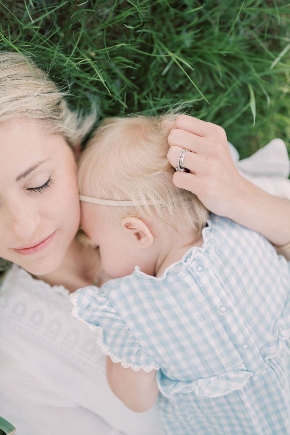 Close-up of parent and baby resting peacefully on green grass.