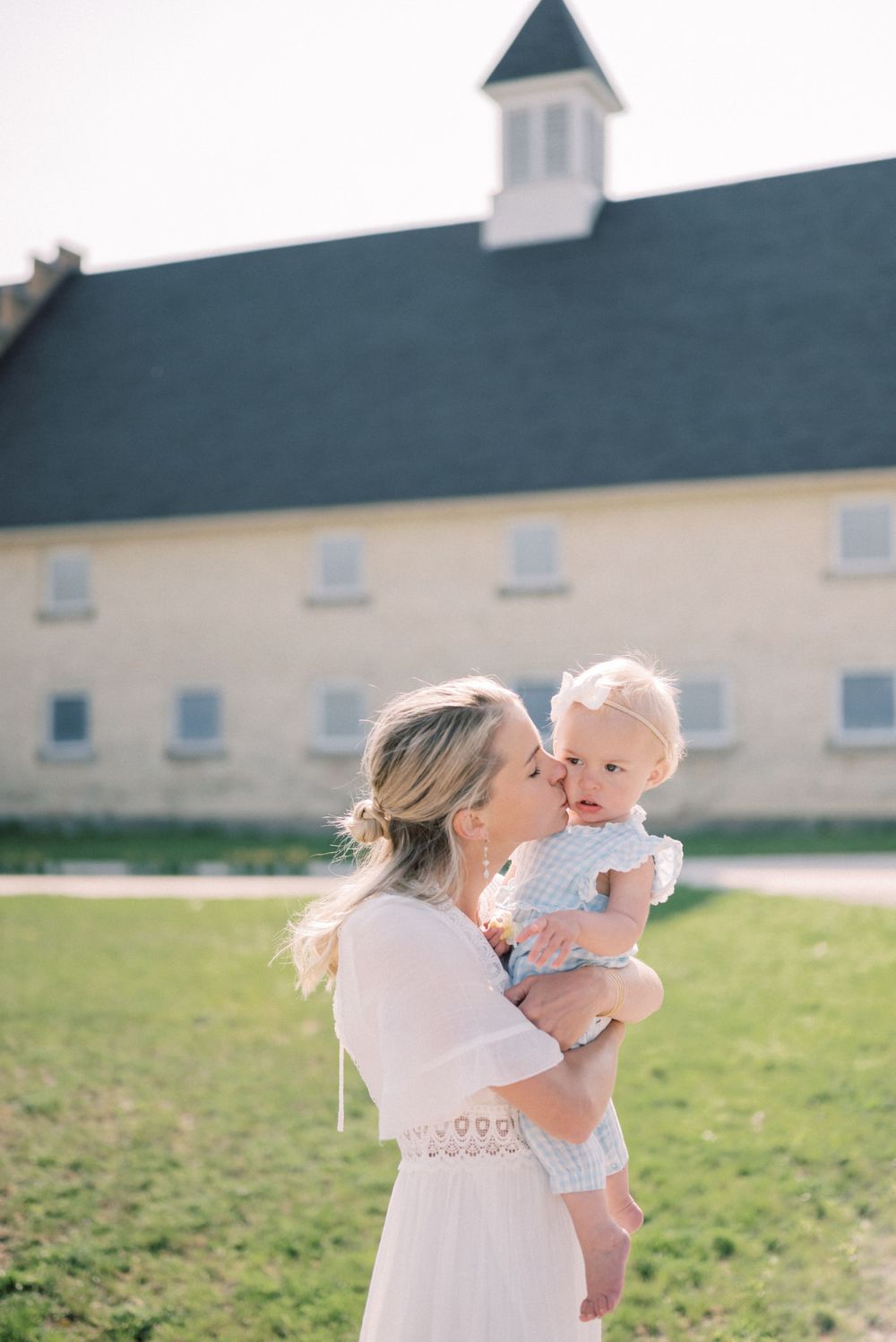 A sunny spring portrait taken in front of a white cottage with a blue cupola.