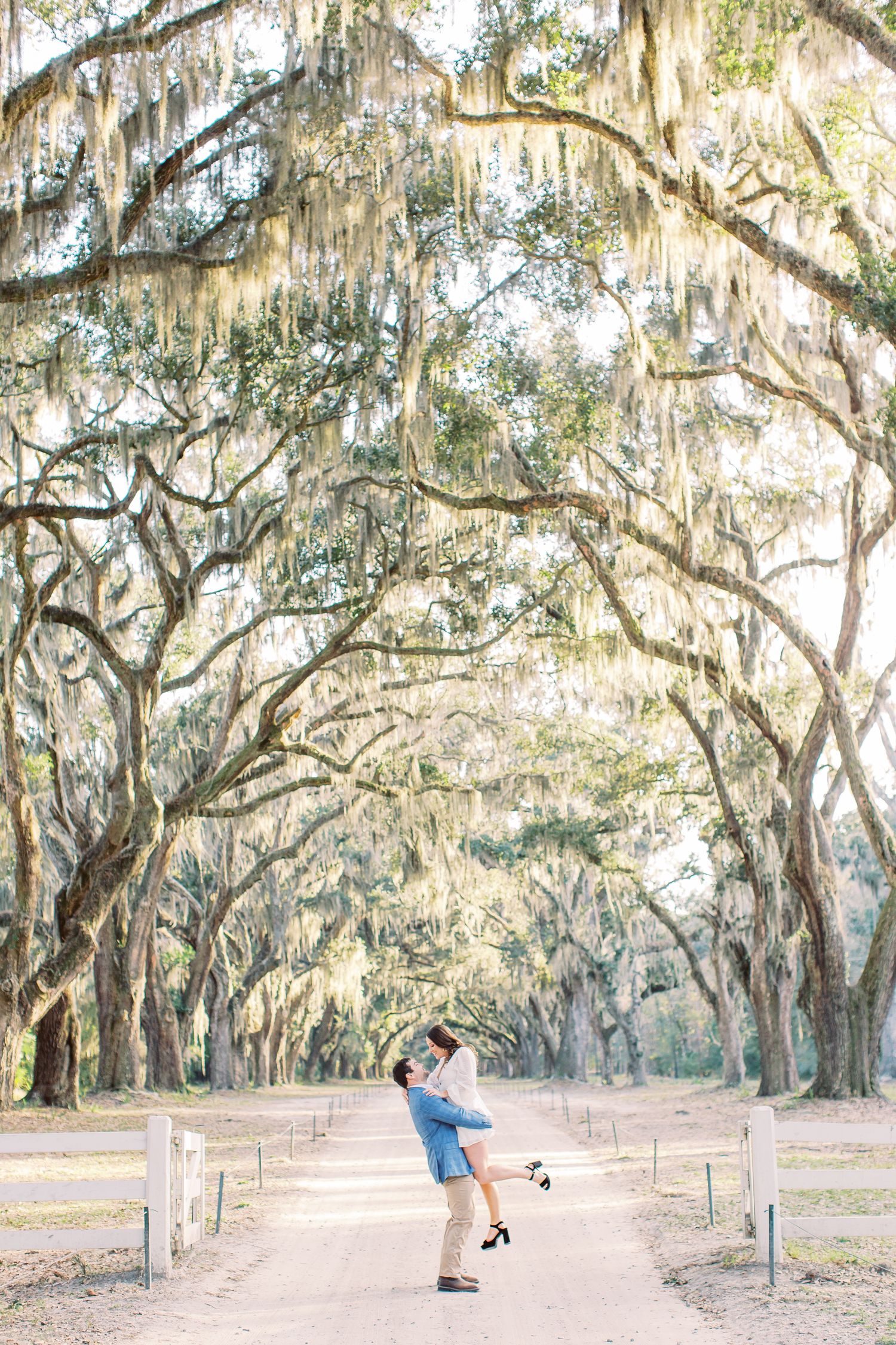 guy lifts girl during engagement session at wormsloe in savannah, ga