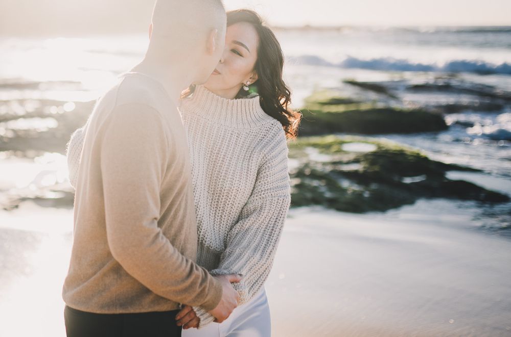 couple stopping for a kiss during sunrise walk on the beach