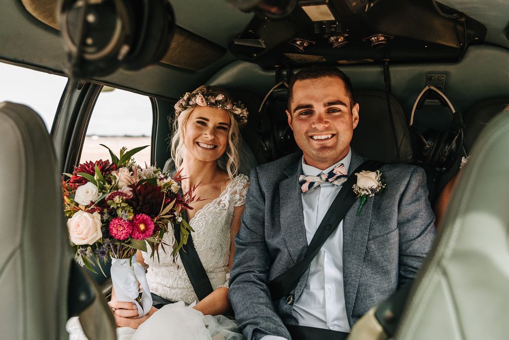 Bride and groom in helicopter with bouquet