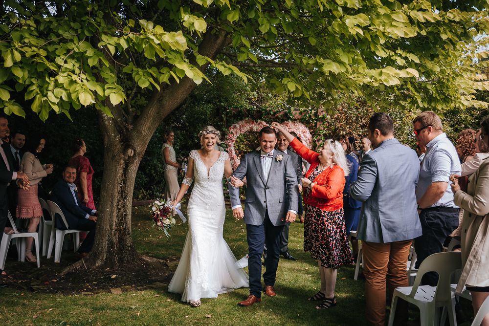 Couple walking down aisle and grandmother throwing confetti at Langdale Vineyard Christchurch