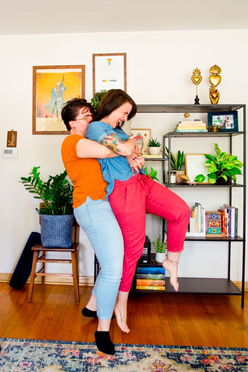 woman in orange shirt picking up woman in pink pants, laughing and flipping her hair for Chicago same sex couple photos
