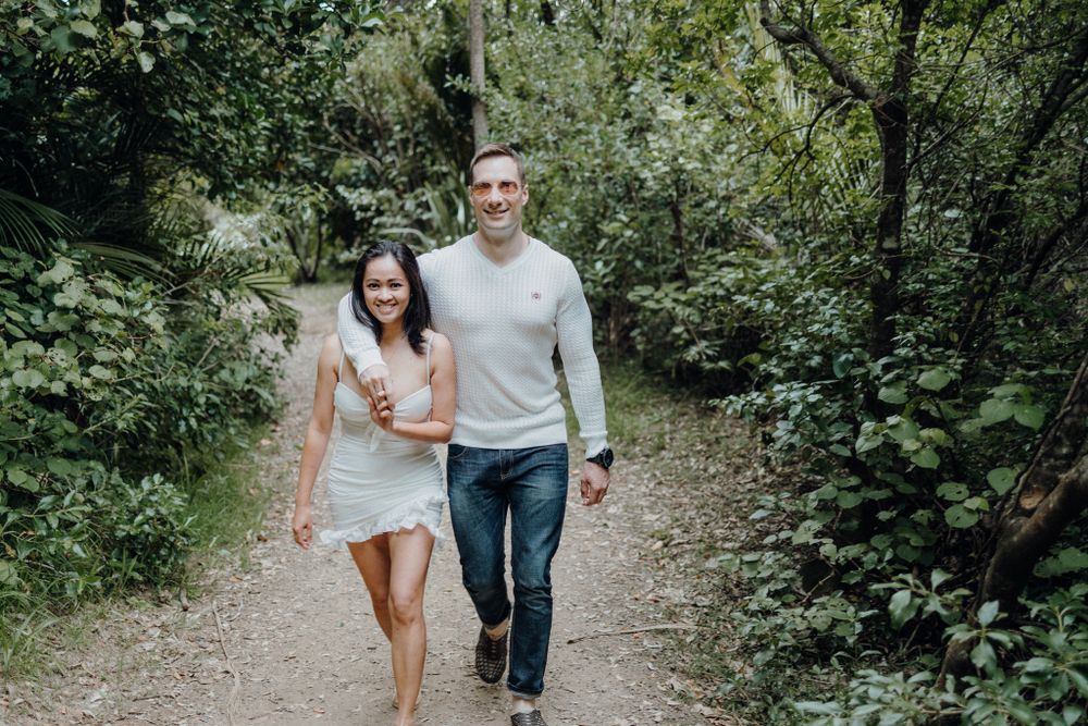 Couple walking together on tree-lined nature path during summer day.