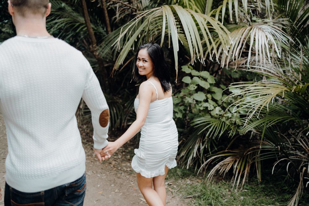 Couple holding hands while walking along tropical garden path.