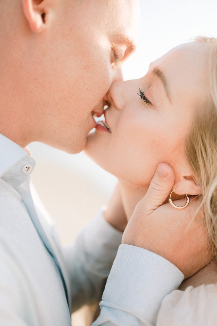 A close-up shot of a couple sharing a tender kiss on the beach.