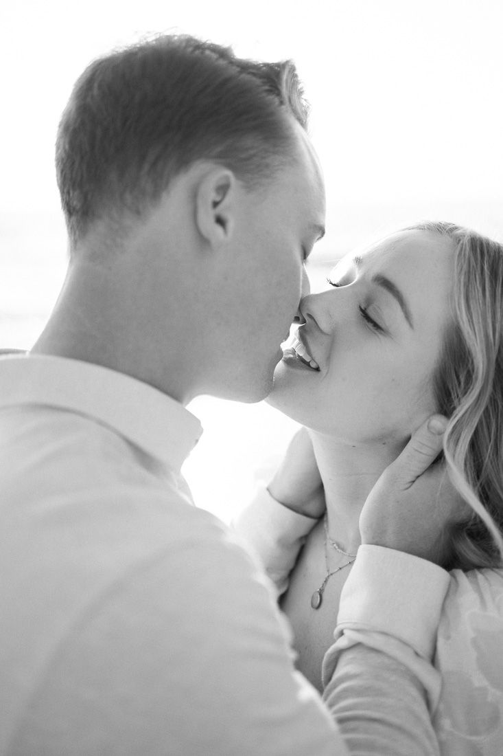 Romantic black and white close-up of a couple sharing an intimate moment with sunlight behind them.