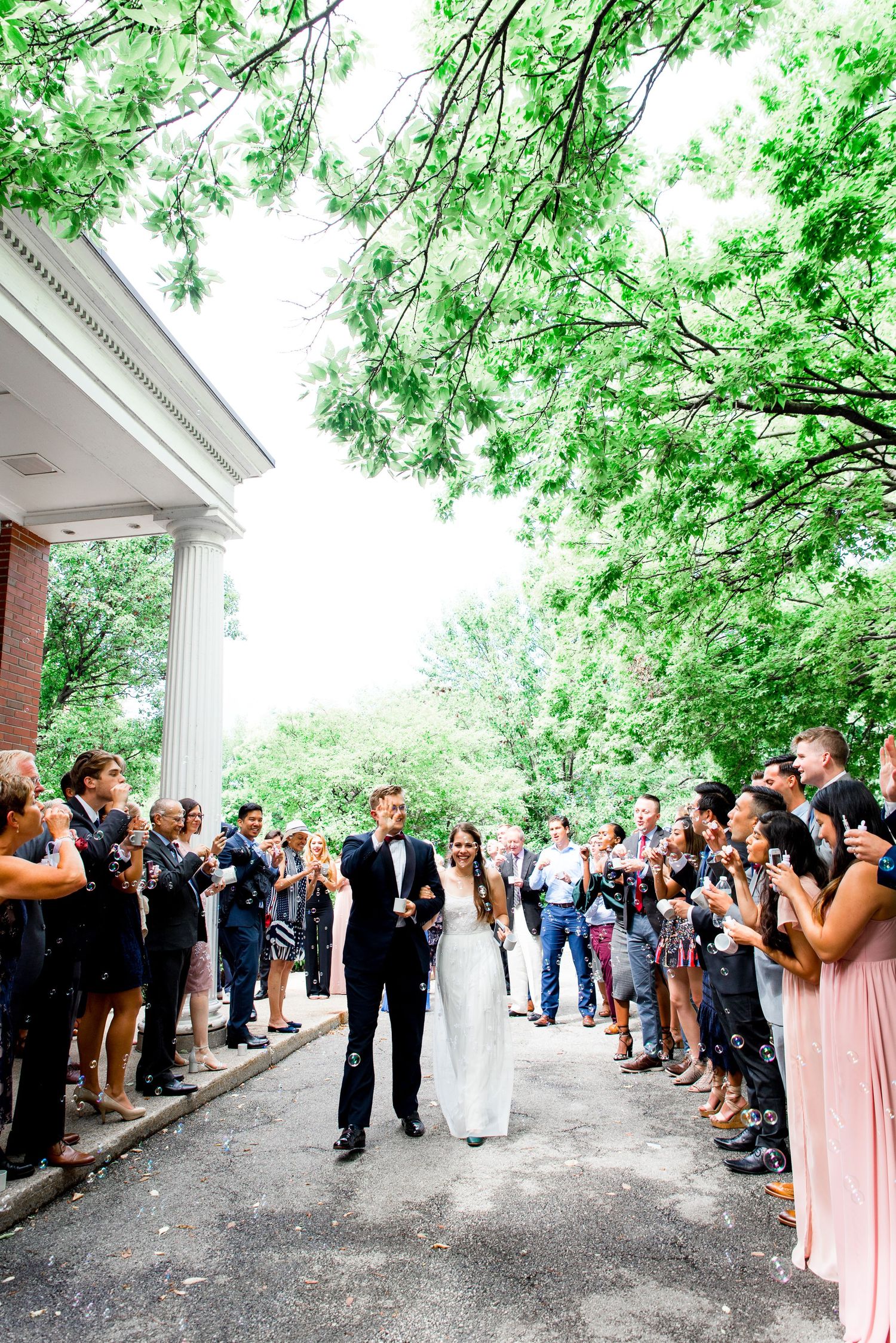 bride and groom holding hands and walking through guests blowing bubbles at Woman's Club of Evanston wedding
