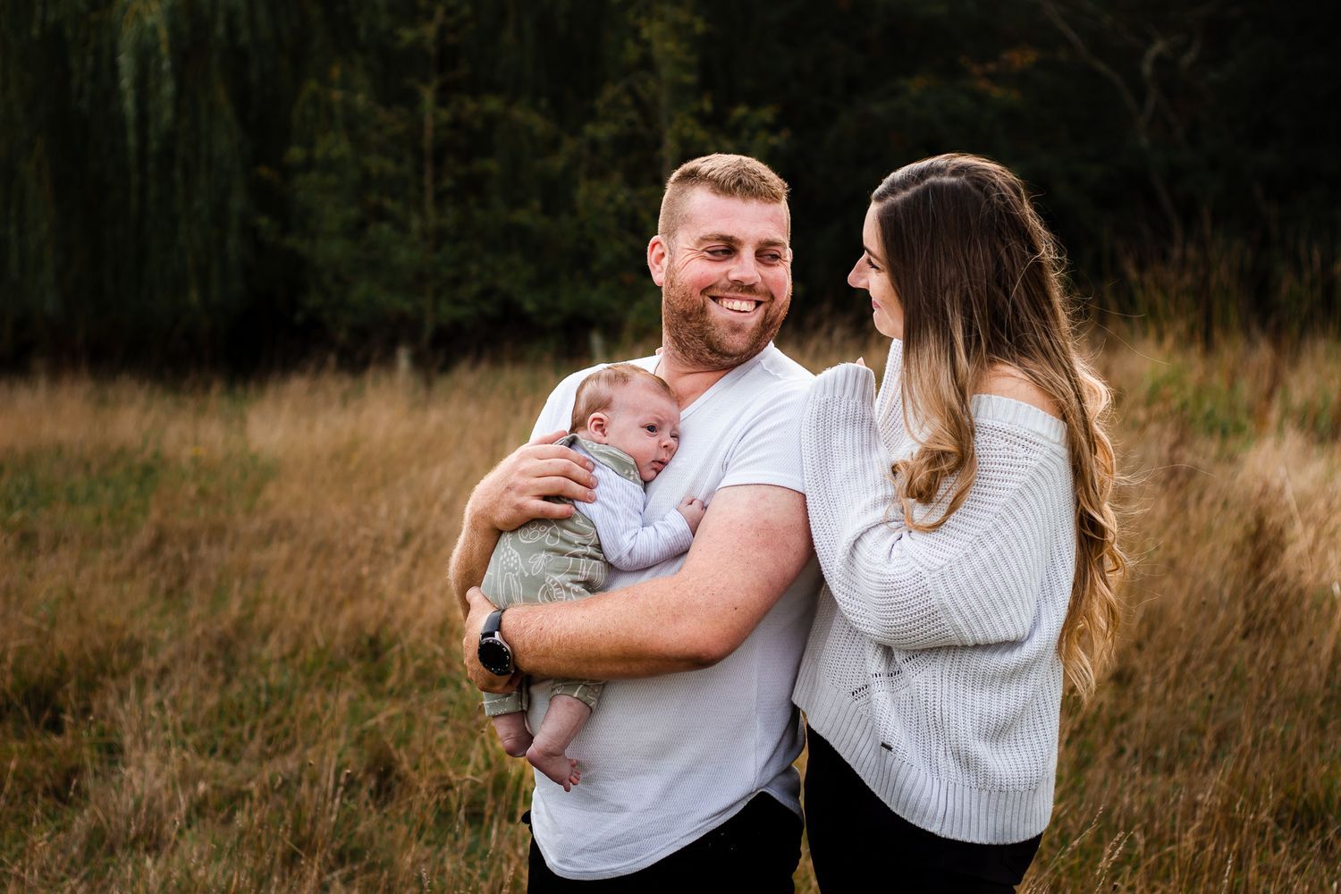 In a field in Havant, Hampshire, new parents smile at each other while holding their newborn baby boy.