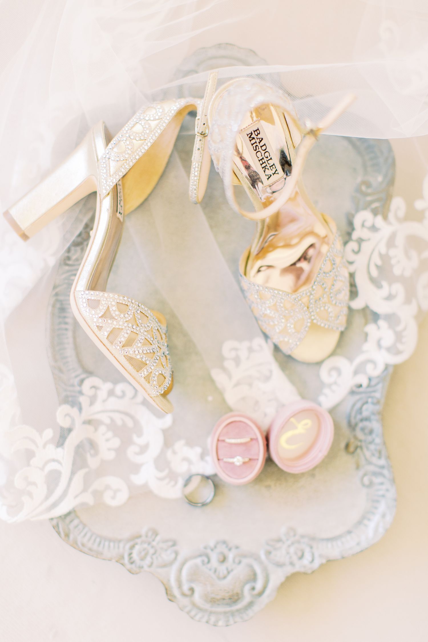 wedding details of badgley mischka shoes and wedding ring on a veil dripped tray
