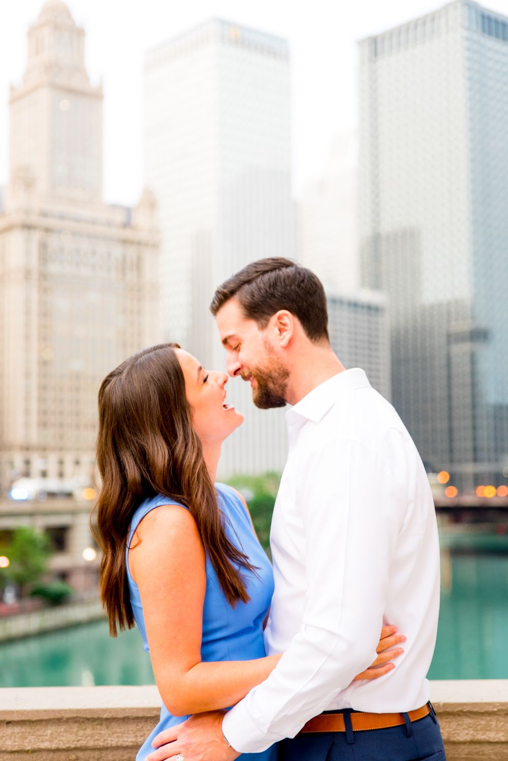 young engaged man and woman looking at each other in front of Chicago River near the Wrigley building at sunrise