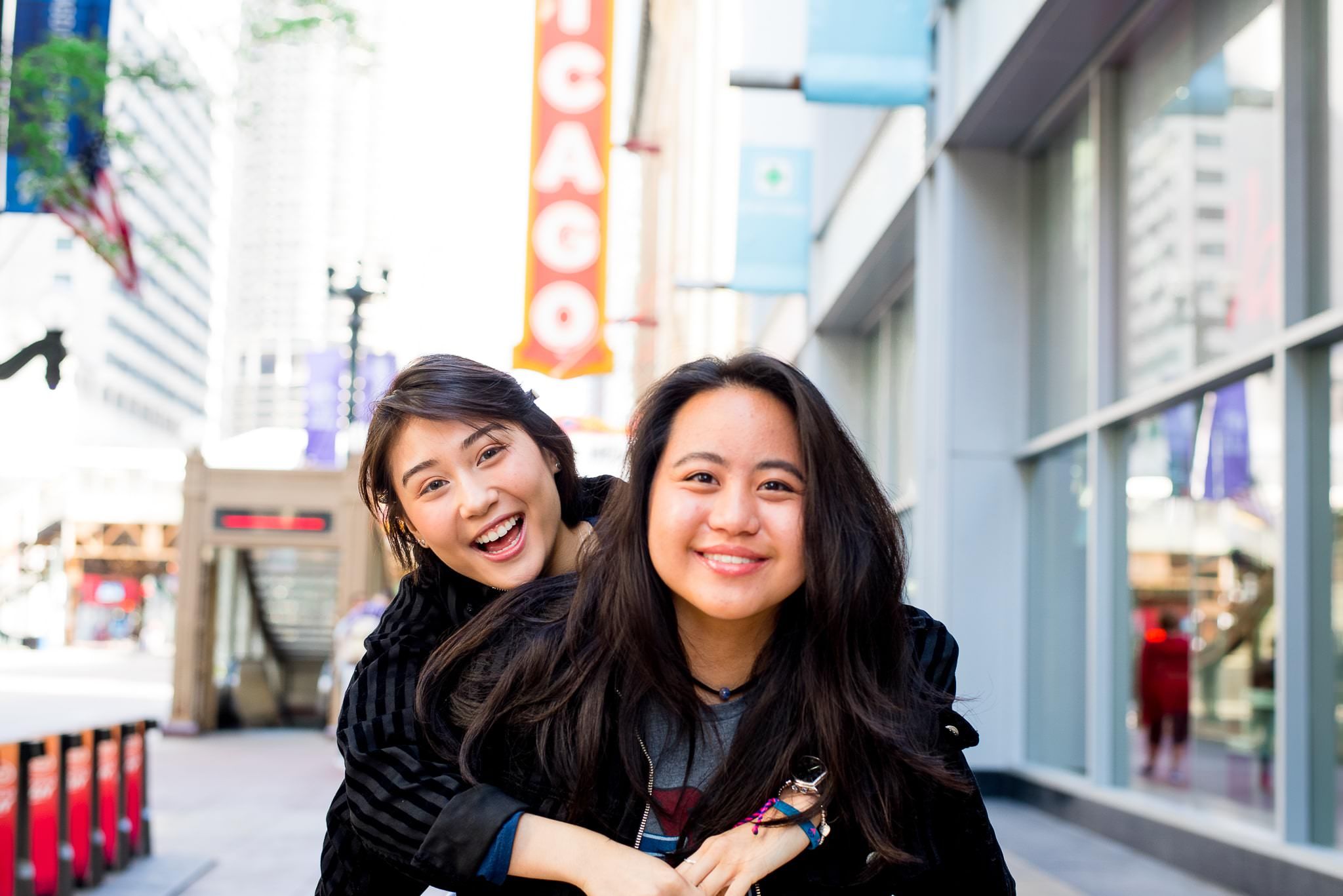 two senior girls in front of the Chicago Theater sign for Chicago senior pictures with piggyback ride