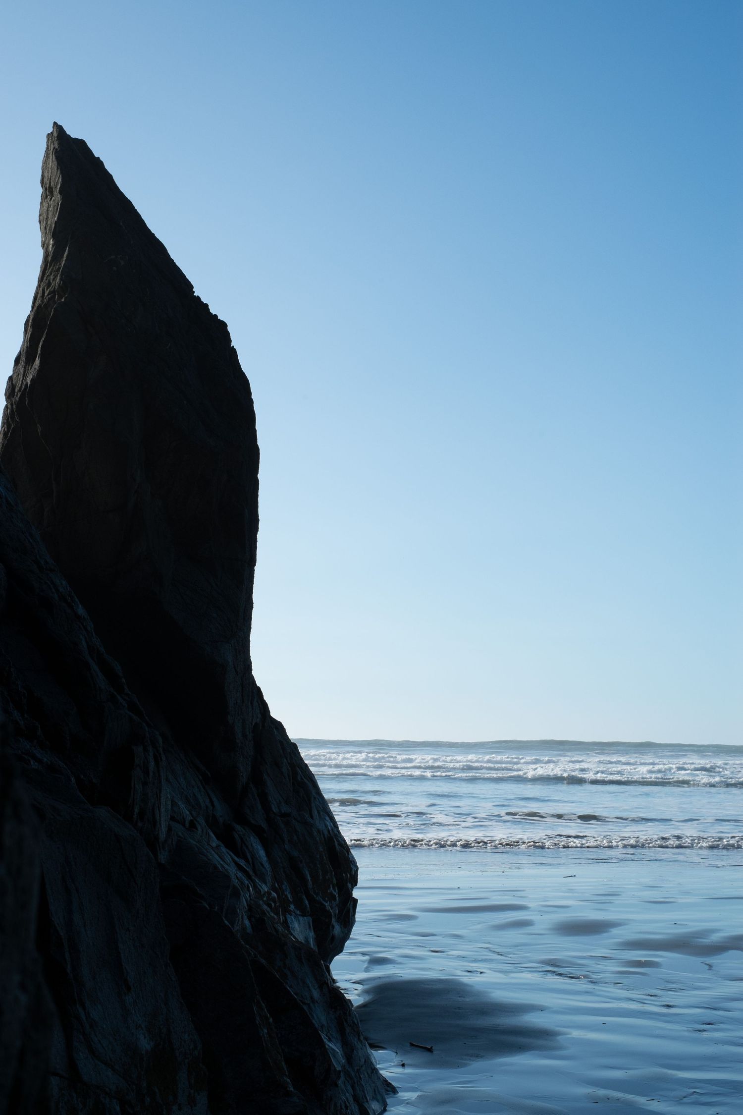 Pacific Northwest Coastal scene of rock in water at low tide by Holli Margell