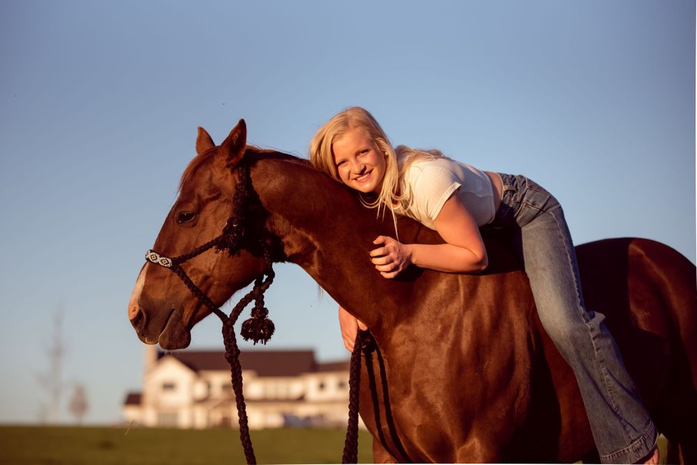Girl wearing white top and jeans on roan colored horse