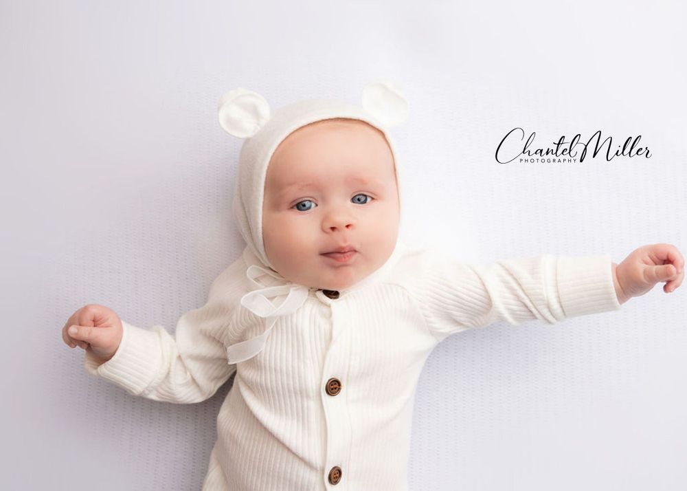 baby boy dressed in white teddybear bonnet