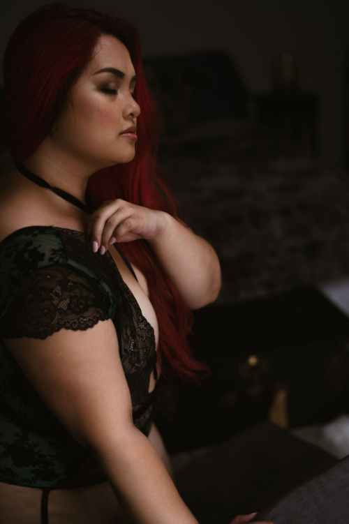 A torso shot of a model in black lace. Her eyes are closed and her expression serene.
