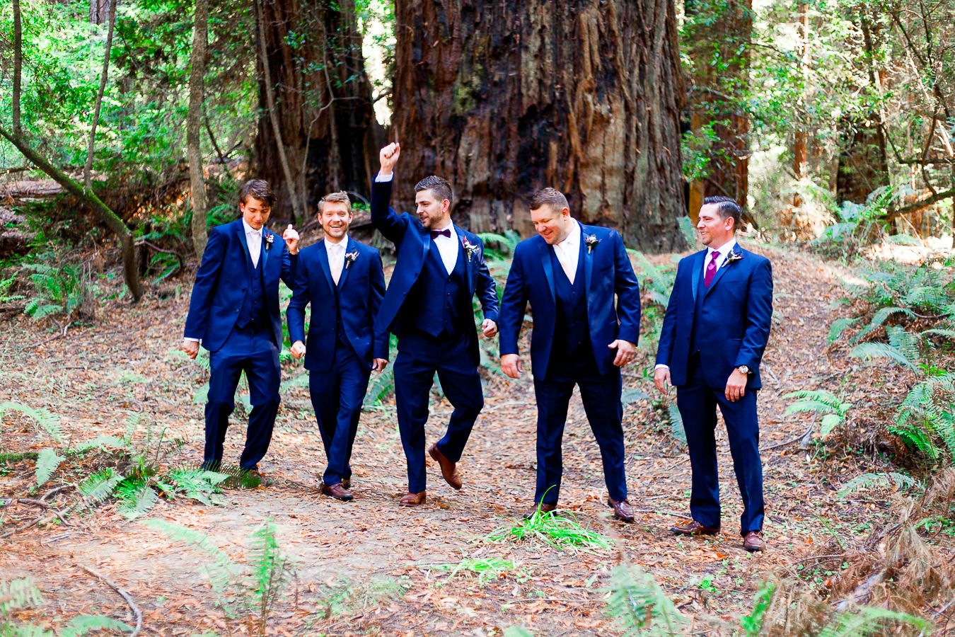 groomsmen and groom in navy suits walk through Hendy Woods State Park in Northern California Redwoods