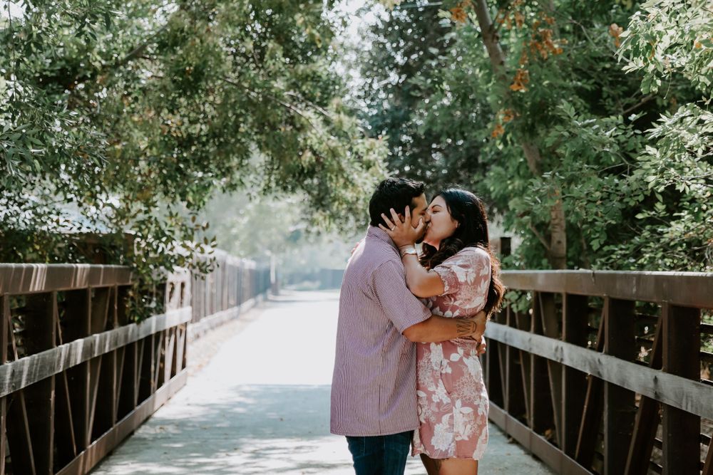 Romantic couple embracing on wooden bridge surrounded by lush greenery.