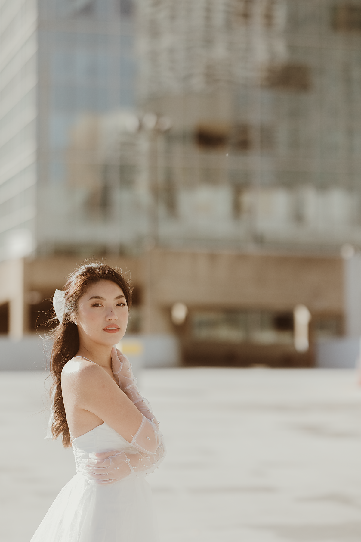 A woman in a white wedding dress poses outdoors in an elegant portrait.