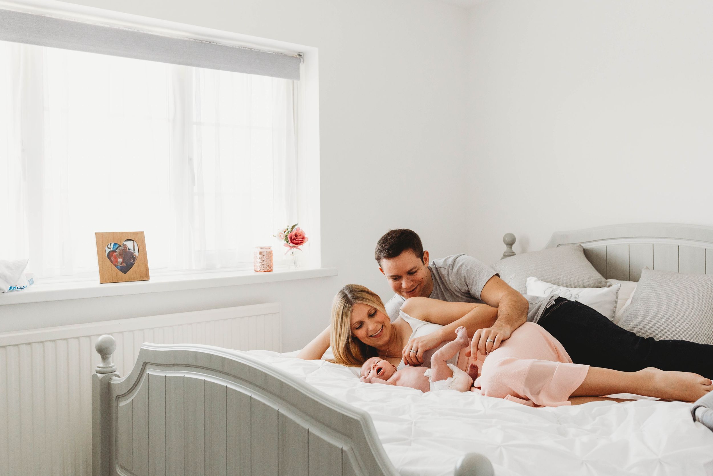 parents with their baby daughter laying on bed