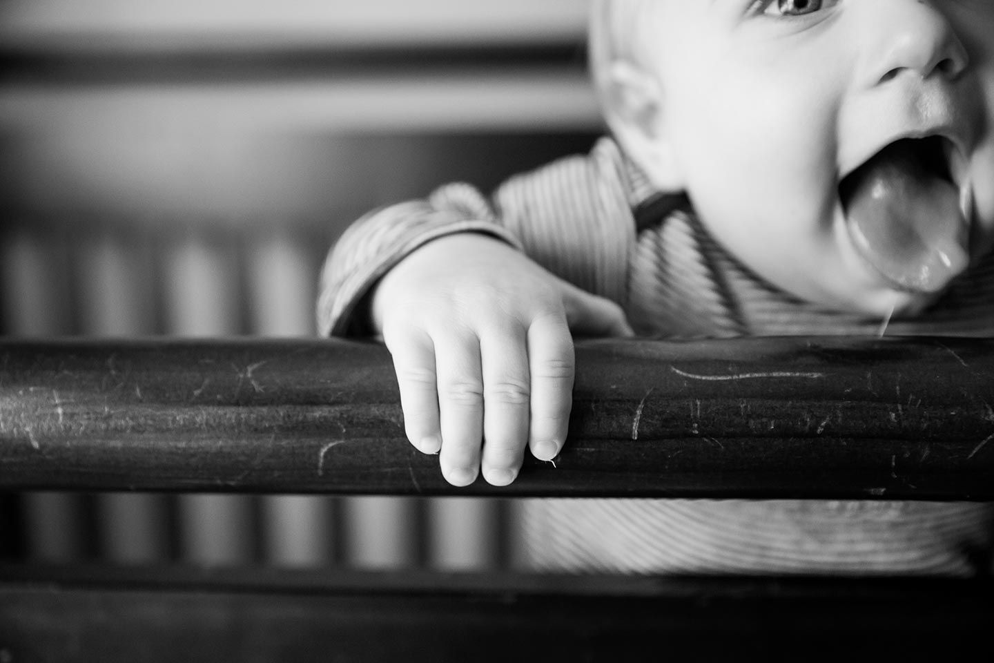 6 month old baby standing in crib and slobbering on crib