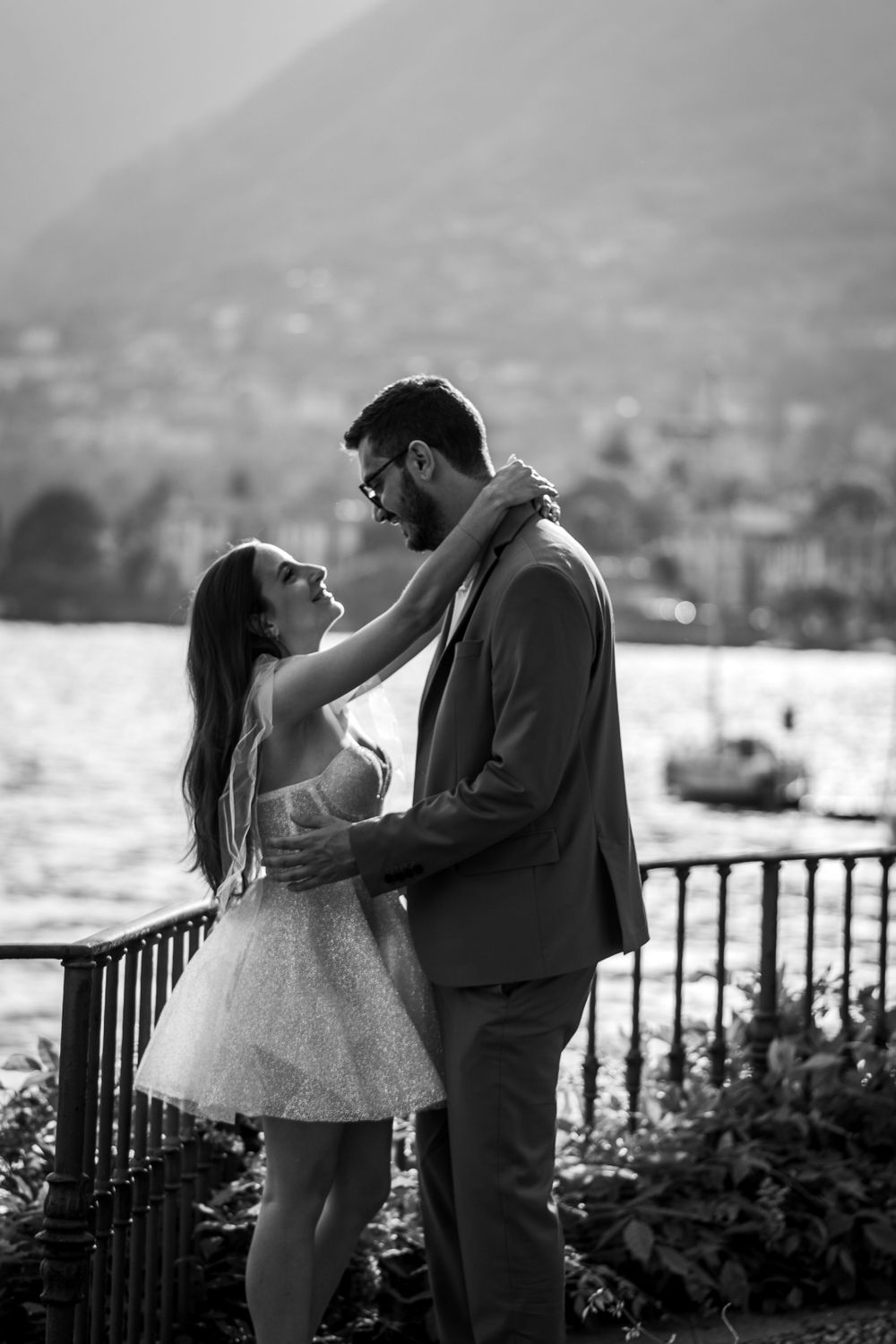 Black and white portrait of a dancing couple sharing a romantic moment by a lakeside railing.