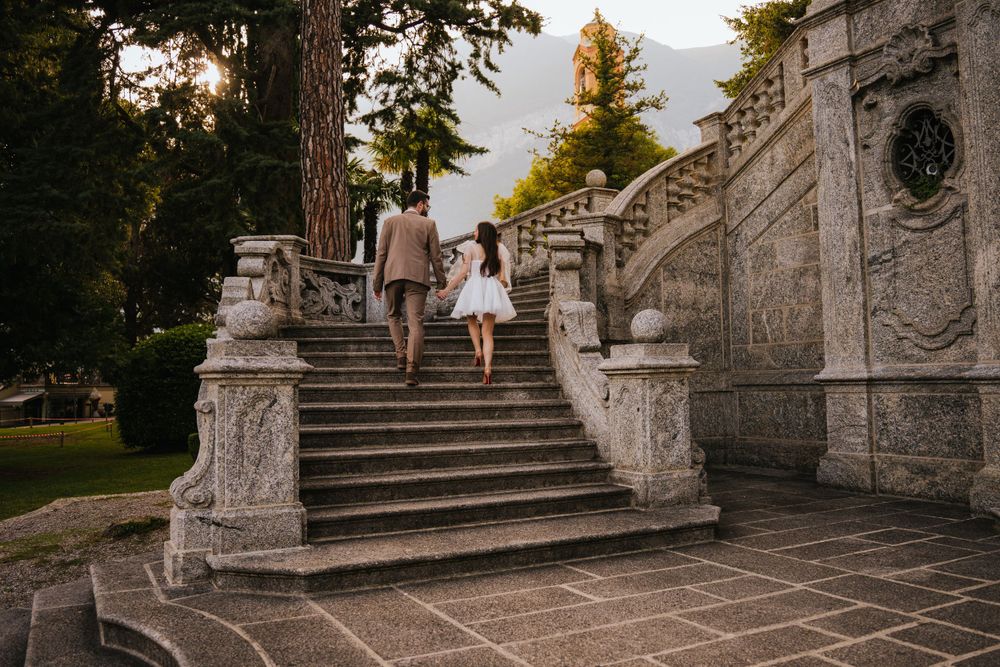Ornate stone staircase with decorative balusters leads up through a scenic garden setting.