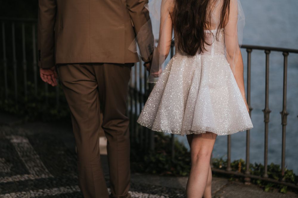 Elegant dancing couple in formal attire twirl together by a scenic lake overlook.