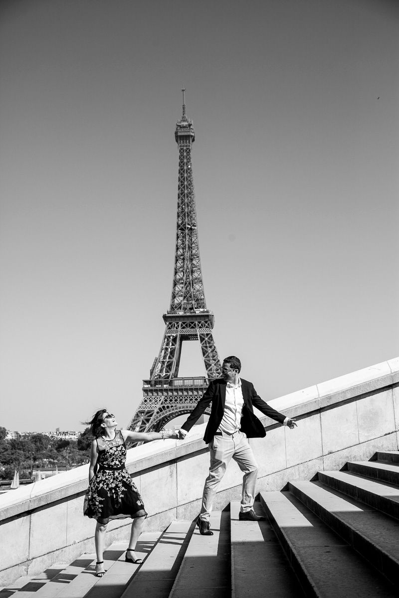 Playful moment captured at the Eiffel Tower steps in black and white photography.
