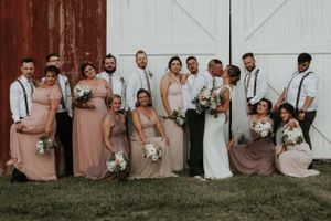 Wedding party posing in front of a barn in the finger lakes