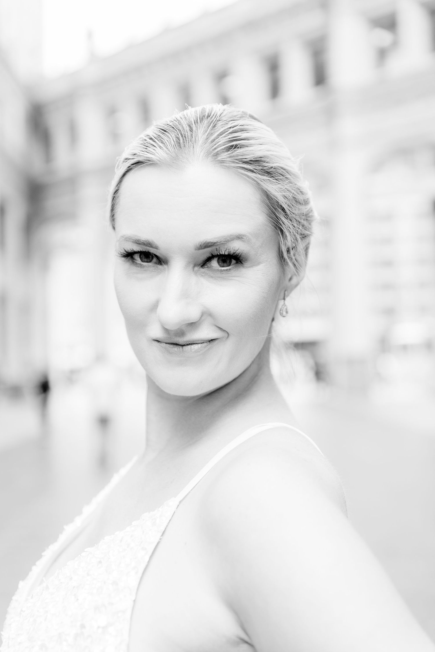 black and white portrait of blonde woman with bun under Wrigley Building
