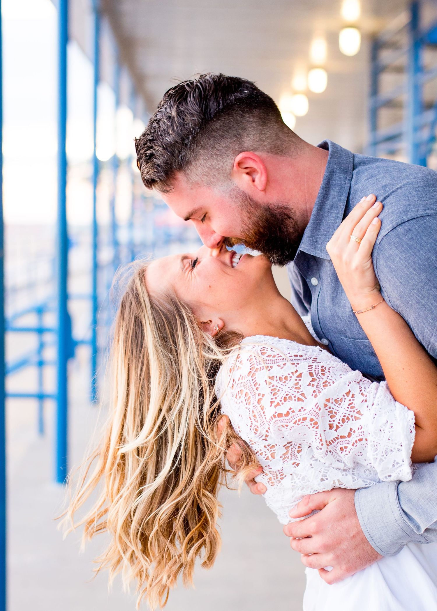 man in blue denim shirt dips and kisses woman in white lace dress at North Avenue Beach Chicago