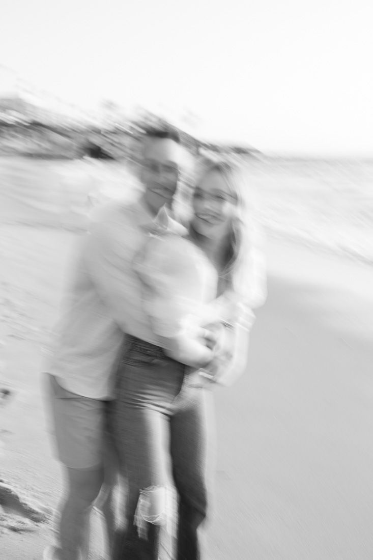 A blurred black and white photo of a couple embracing on a beach.