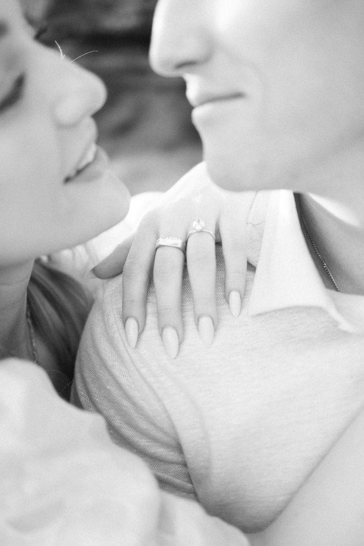 A close-up black and white photo showing an engagement ring and tender embrace.