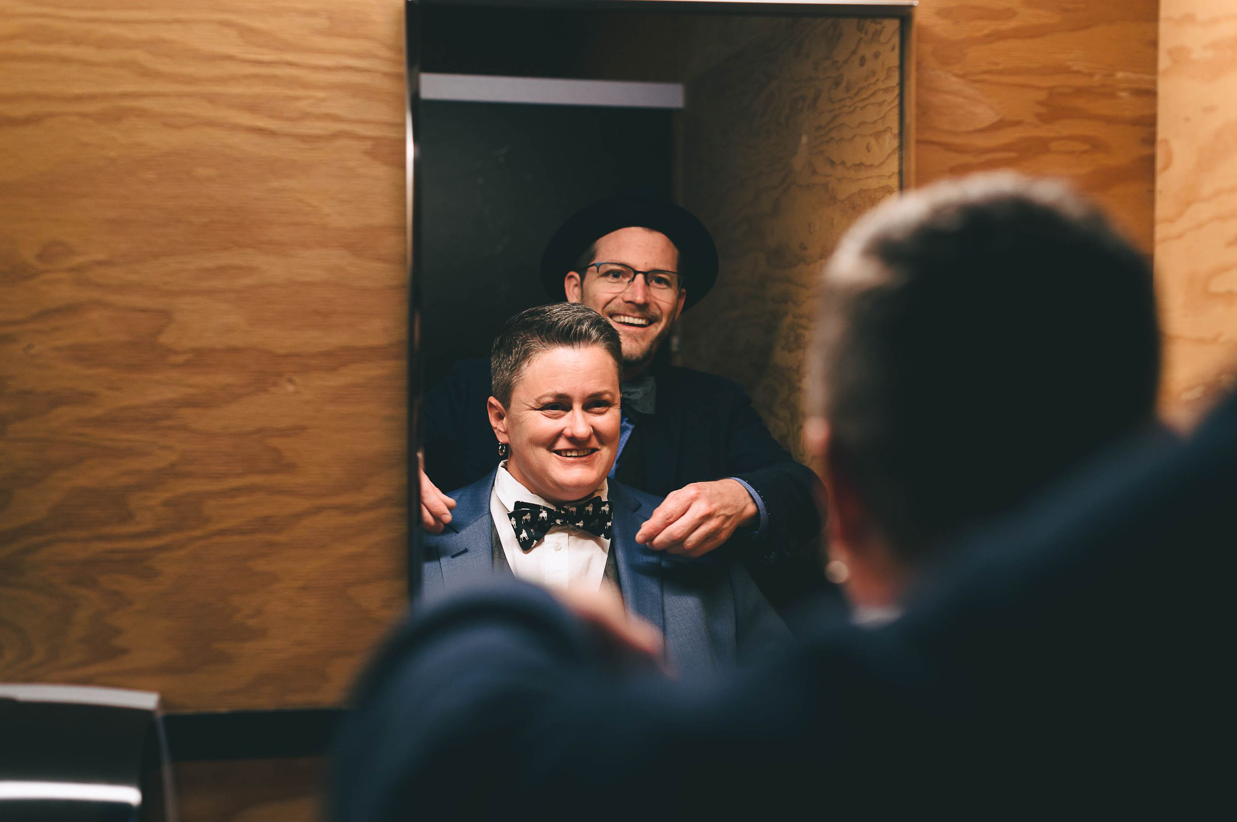 Lesbian having a laugh while putting on bow tie for wedding.