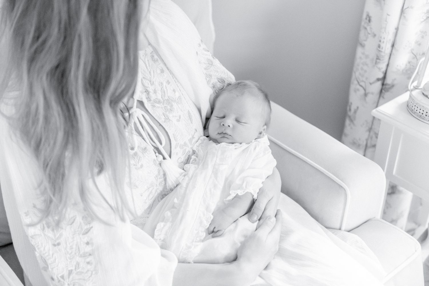 Black and white image of a mother cradling her newborn baby in the nursery rocking chair.