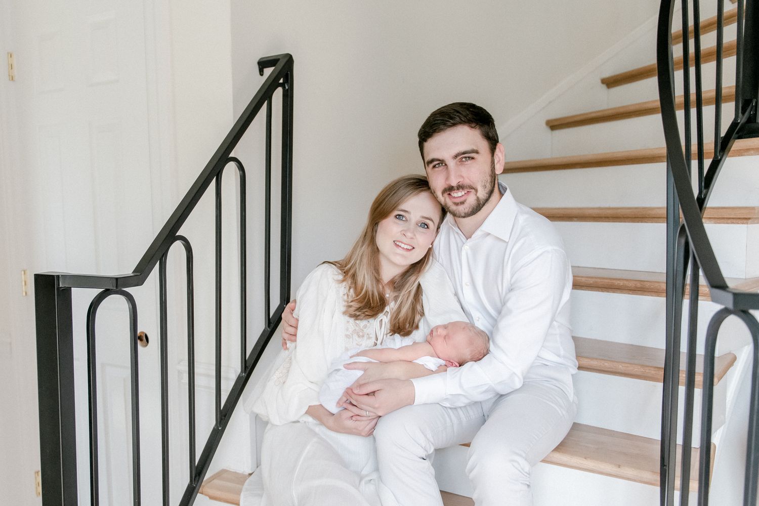 Family smiles at the camera as they sit on their Franklin, TN home stairwell