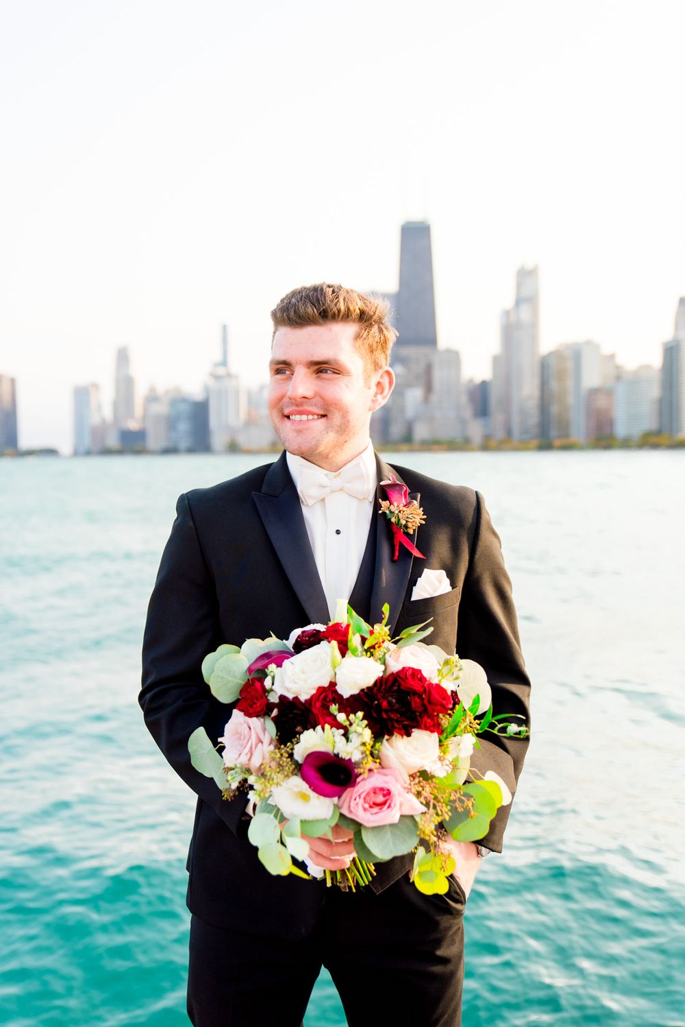 chicago groom holds the brides bouquet near chicago city skyline