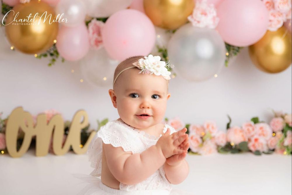 baby girl with pink and gold balloons