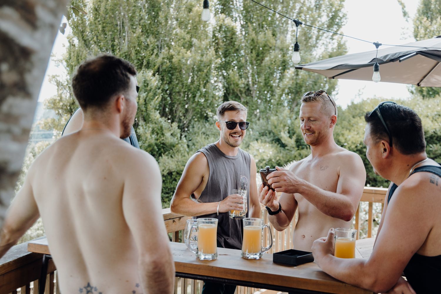Friends socializing and drinking beers at outdoor patio table.