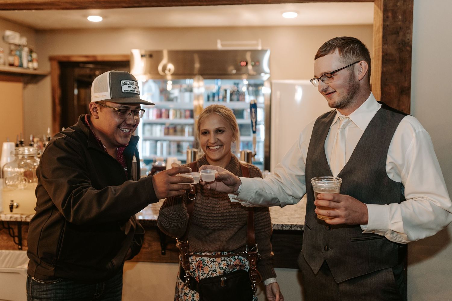 Wedding guests sharing drinks and toasting at the venue bar.