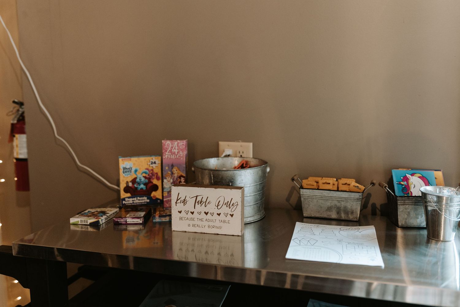 Wedding reception display table with snacks and signs arranged on metallic surface.