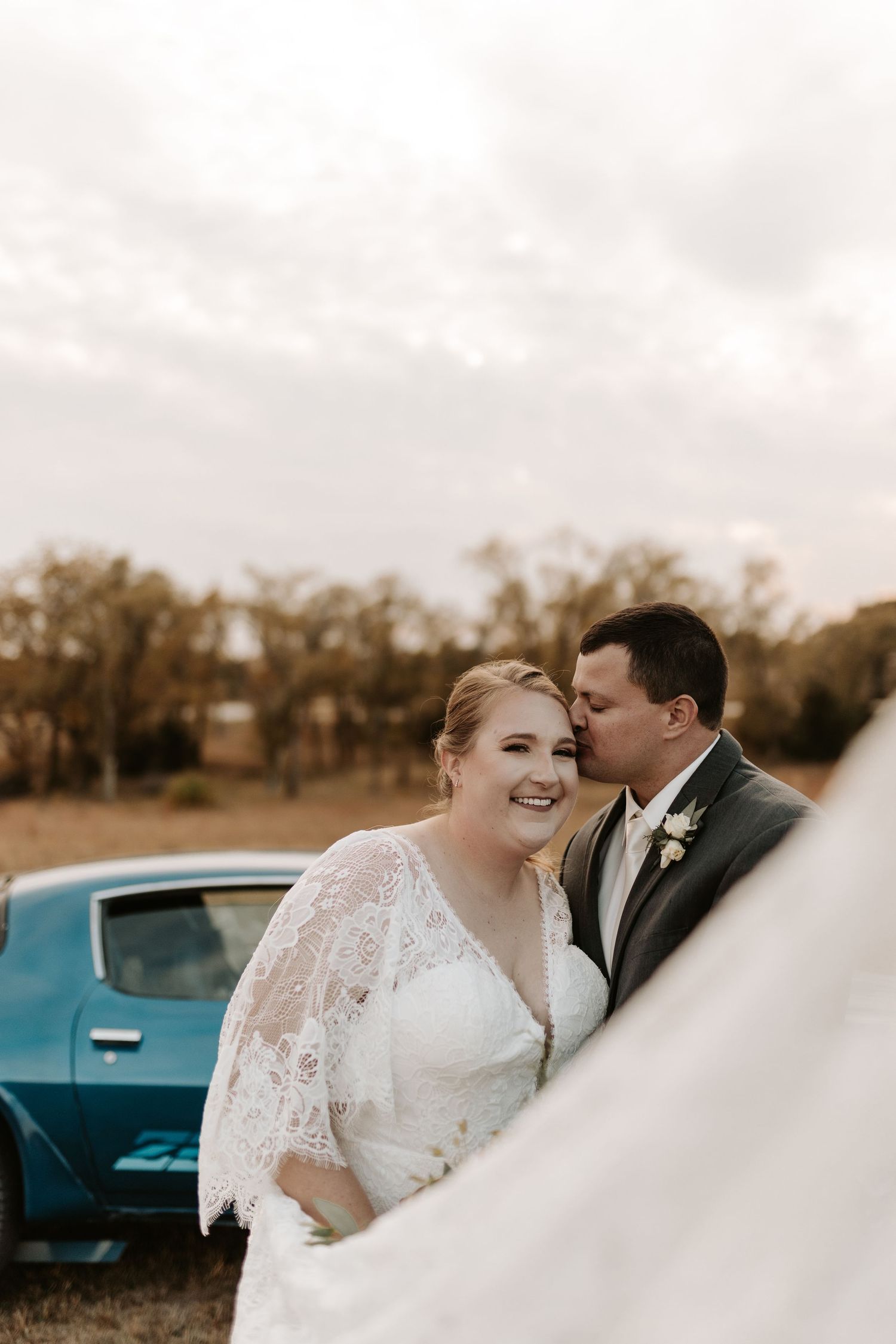 A tender wedding portrait with a vintage turquoise car in the background.