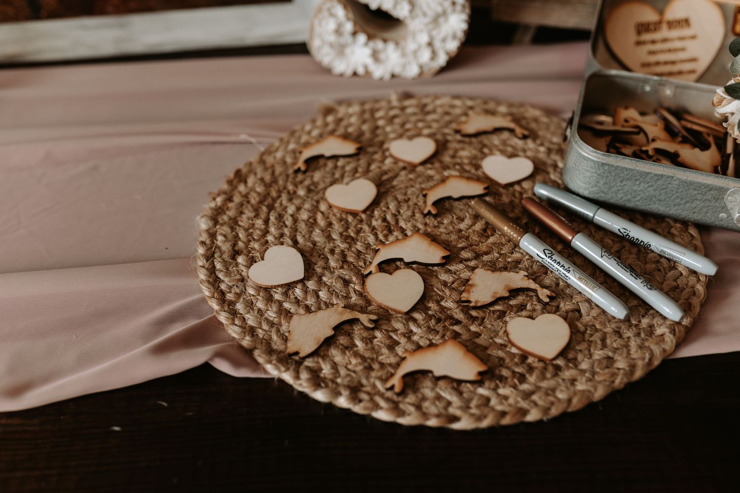 Decorative placemat with wooden hearts and metallic pens for wedding guest book.