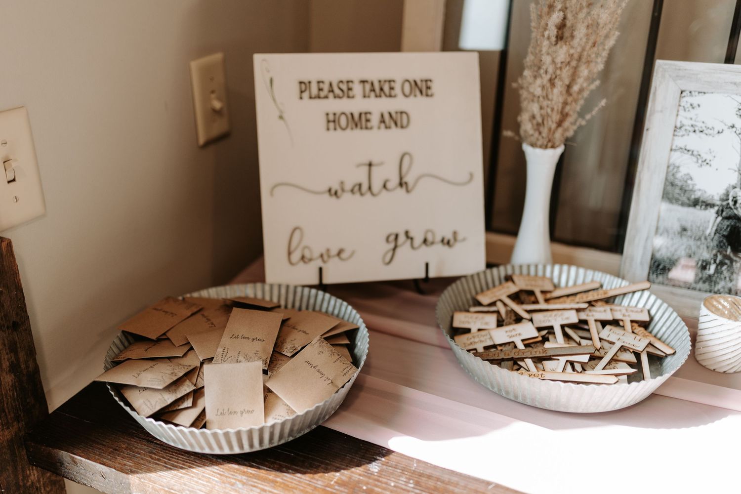 Wedding favor display with wooden sign and plates of treats for guests.