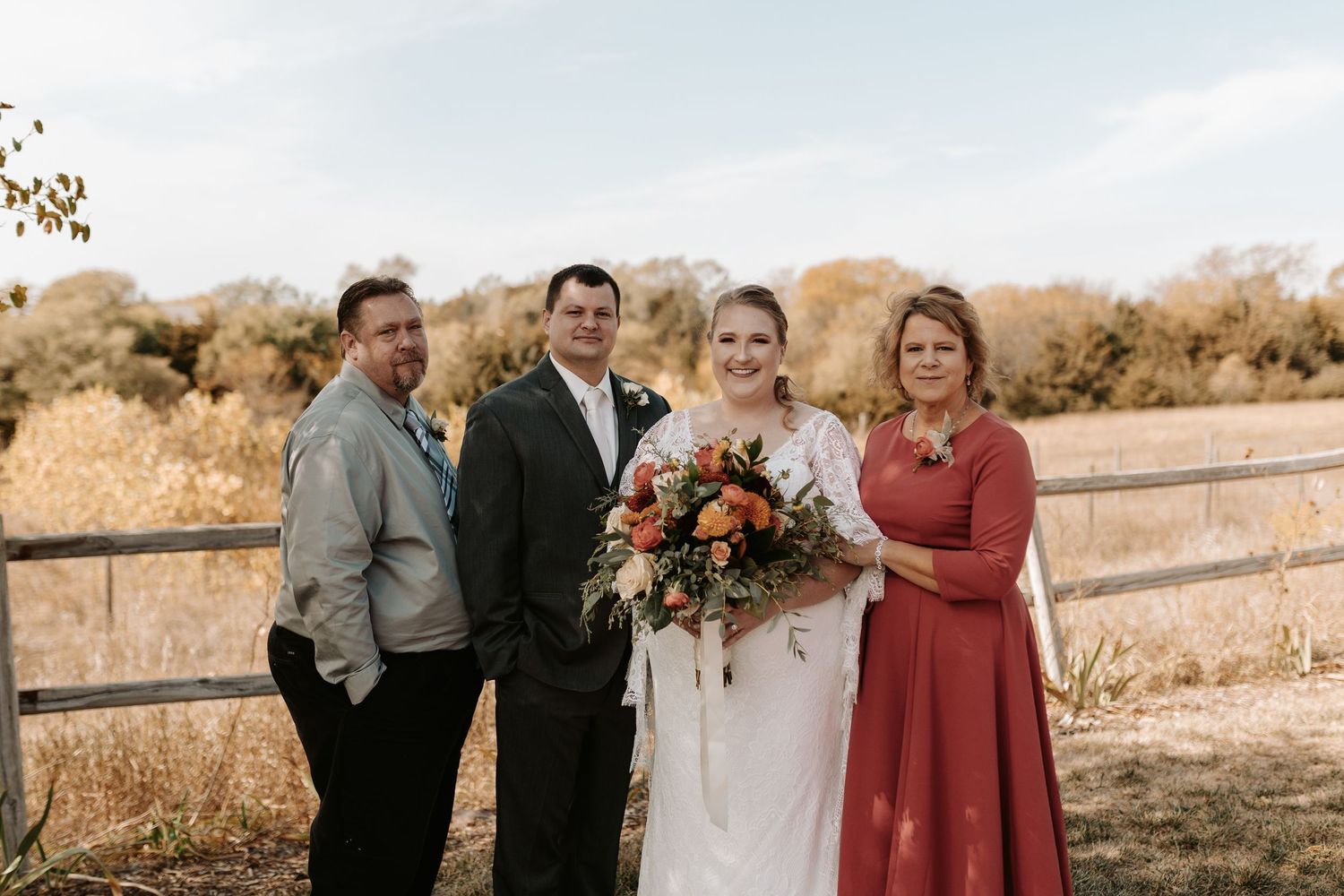 Small group portrait outdoors with wedding party members in formal attire.